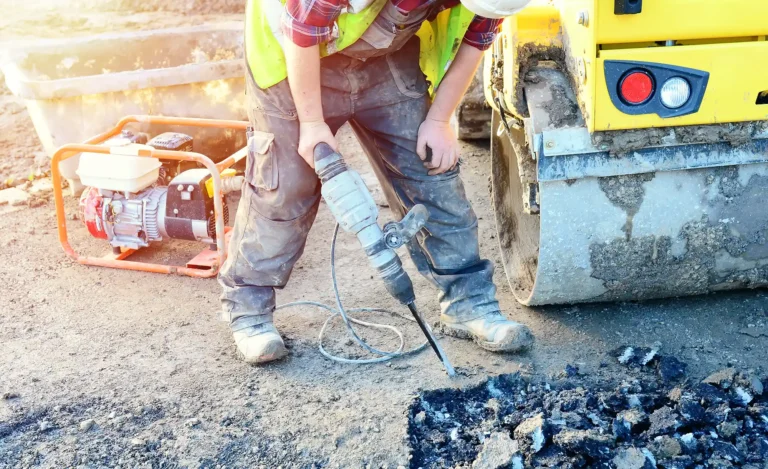 Builder breaking asphalt with electric breaker